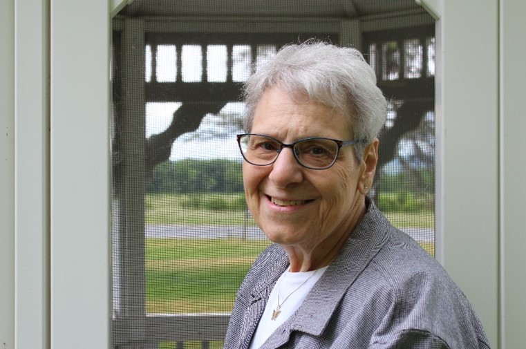 An outdoor portrait of Anne Marie Farage-Smith. Farmland is visible in the background, through a gazebo.